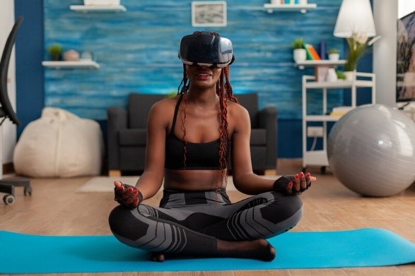 A girl sitting on the floor with her legs crossed with a VR headset on.