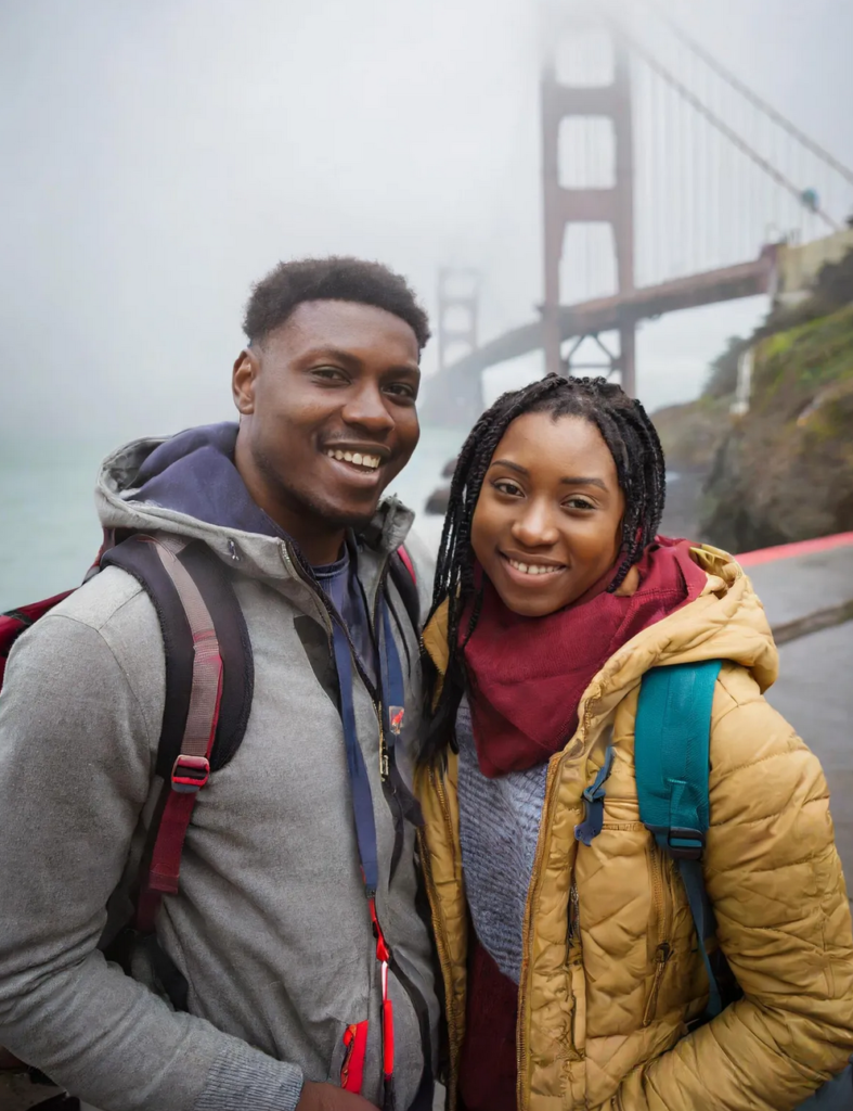 An AI generated picture of a couple standing outside with a large bridge behind them.